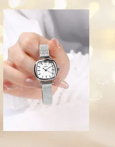 Close-up of a square silver quartz watch with a mesh strap held by a model