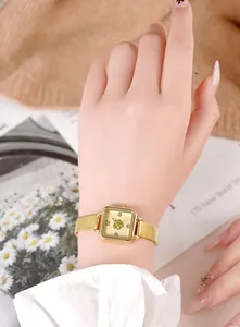 Close-up of elegant gold square quartz watch for women with flower dial and woven metal strap