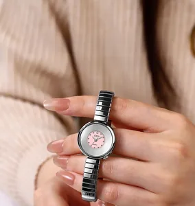 Detail view of the pink dial quartz watch with a silver elastic band on a soft background
