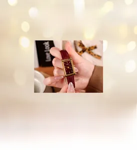 Macro shot of rectangular quartz watch with deep red dial and golden case detail