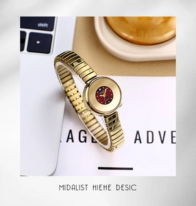 Detailed view of women's gold quartz watch with a small deep red dial on a keyboard