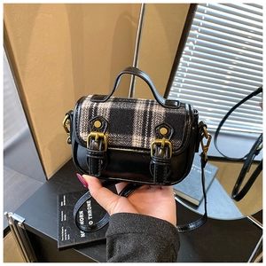 Detail of vintage wool plaid bag with black leather patchwork and gold metal buckles