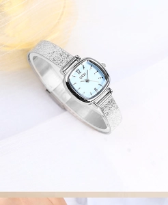 Detail of square silver watch with light blue dial and textured metal strap