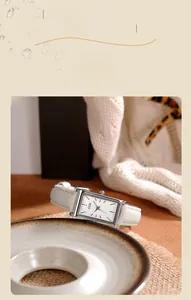 Detailed close-up of a GEDI square silver watch with a white leather strap on a soft surface