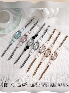 Macro shot of seven oval quartz watches with geometric linked bracelets on white fabric
