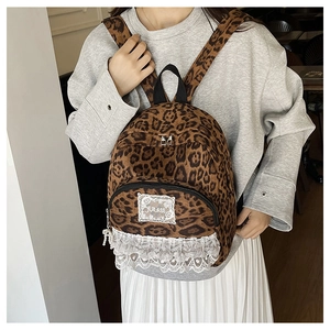 Détail du sac à dos léopard avec bordure en dentelle blanche et étiquette de marque