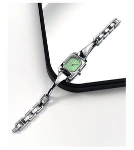Detailansicht einer silbernen quadratischen Quarzuhr mit hellgrünem Zifferblatt und Gliederarmband