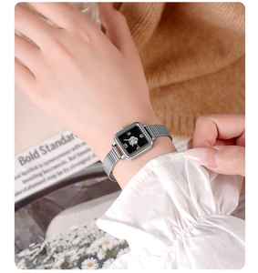 Close-up of square silver mesh watch with black dial and floral pattern on a model wrist