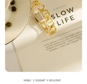 Close-up of golden rectangular quartz watch with designer H-shaped metal chain strap
