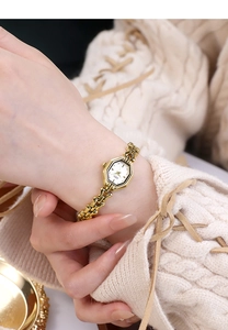 Detail of elegant gold octagon watch with white dial on a warm knit sweater sleeve