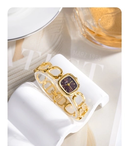 Detail of GEDI small square quartz watch with gold link bracelet on a white display stand