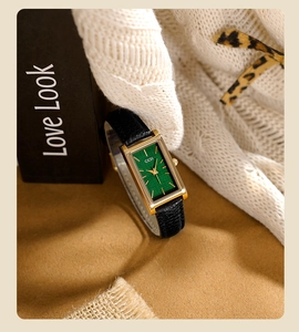 Close-up of rectangular gold watch with green textured dial and black leather strap