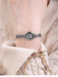 Close-up of elegant octagonal silver watch worn over a beige knitted sweater
