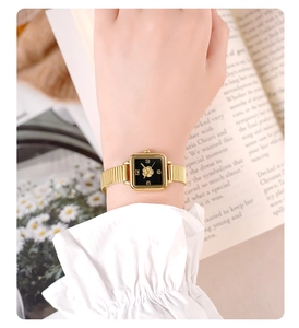 Detailed view of women's square gold watch with floral relief dial on a vintage book