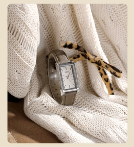 Detail of vintage square quartz watch with grey leather strap on a soft knit sweater