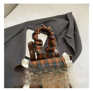 Dettaglio zaino in tweed a scacchi con manico a volant e finiture in pizzo e orsetto
