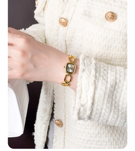 Close-up of vintage square gold bracelet watch worn with white tweed jacket