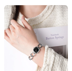 Silver chain bracelet watch with a black rectangular dial on a woman's wrist