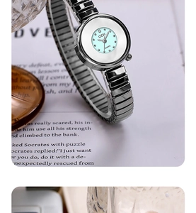 Macro shot of silver elastic band watch on book showing the light blue and white dial