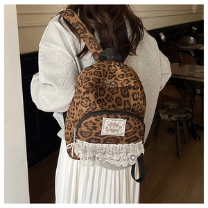 Détail du sac à dos léopard avec bordure en dentelle blanche et breloque en perle élégante