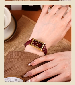 Close-up of elegant square burgundy watch with gold case and textured leather strap