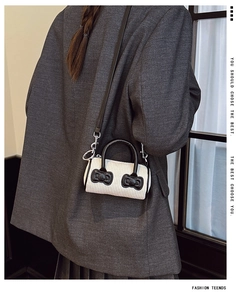 Detail of mini off-white corduroy bucket bag with black bows and adjustable strap