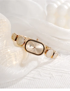 Detail of Gedi gold oval watch with decorative marble-textured bracelet on silk background