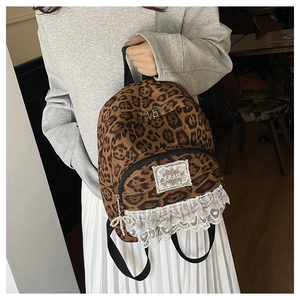 Détail du sac à dos léopard avec bordure en dentelle blanche et charm nœud en perles