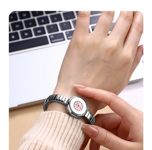 Detailed shot of woman wearing a silver elastic strap watch with a pink dial on wrist