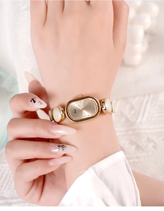 Close-up of elegant gold oval dial watch with minimalist link strap on a wrist