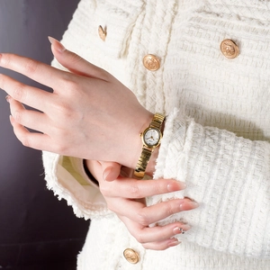 Elegant gold metal stretch band watch with white oval dial on female model's wrist