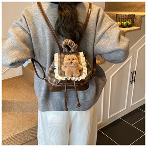Vista posteriore di un bambino con mini zaino a quadretti con pizzo e orsetto decorativo