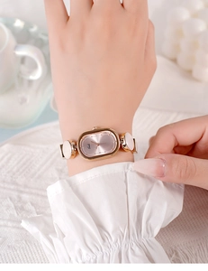 Detailed shot of an oval rose gold quartz watch with a decorative link bracelet strap