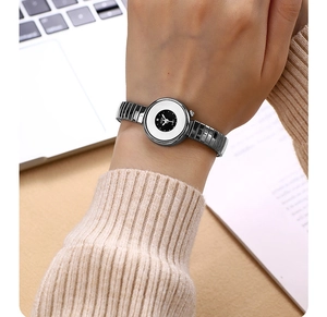 Close-up of a small round women's quartz watch with a silver elastic band on a wrist