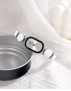 Close-up of Gedi watch featuring an oval dial with silver sunray pattern and white ceramic band