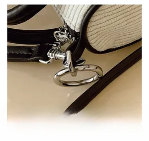 Detail of silver metal rings and black leather strap on corduroy bucket bag