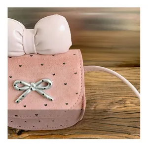 Dettaglio della borsa a tracolla in camoscio rosa con stampe a cuore e cuciture fini