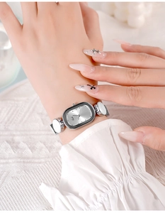 Close-up of elegant oval silver watch with stone-inlaid bracelet strap on female wrist