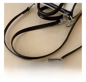 Close-up of adjustable leather strap and silver metal buckle on corduroy bucket bag