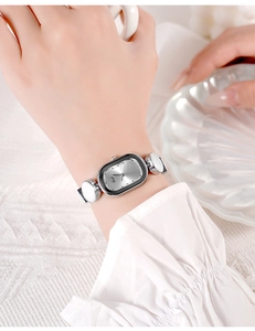 Close-up of elegant oval women's quartz watch with silver metal case and white details