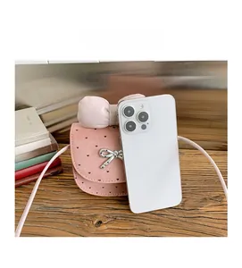 Mini borsa a tracolla rosa con fiocco e cuori, mostrata accanto a un cellulare