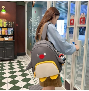 Détail d'un sac à dos pingouin mignon avec pendentif en peluche et poche jaune