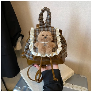 Dettaglio zaino per bambini a scacchi con pizzo e orsetto di peluche marrone