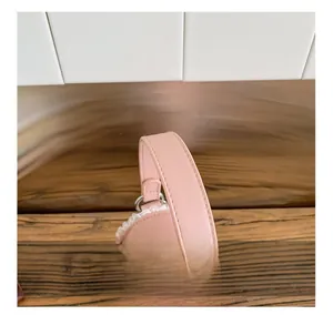 Détail d'un sac à main rose en cuir avec dentelle blanche et poignées surpiquées