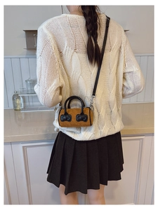 Close-up of a mini yellow velvet bucket bag with black bows worn by a child model