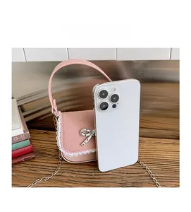 Mini sac rose avec nœud argenté et dentelle posé à côté d'un iPhone pour comparer la taille
