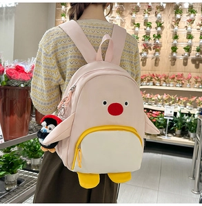 Vue détaillée du sac à dos pingouin rose avec peluche porté par un mannequin en boutique