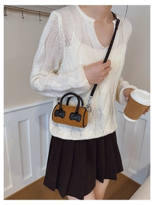 Detail of brown corduroy mini bucket bag with leather bows on beige sweater outfit