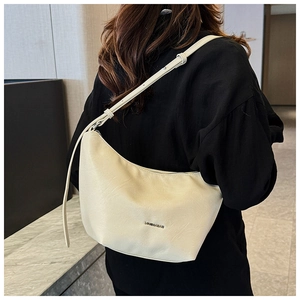 Close-up of beige leather shoulder bag with gold branding and adjustable strap detail