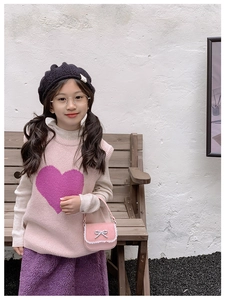 Fille en gilet rose et jupe violette tenant un mini sac à main avec nœud et dentelle